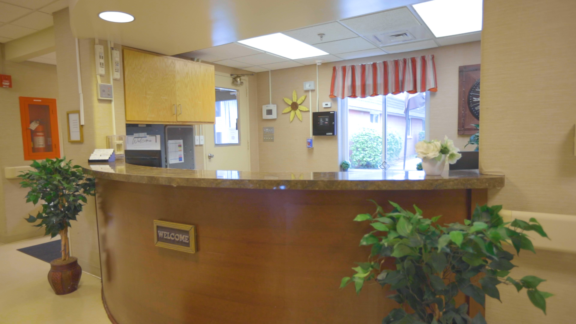 Front Desk with welcome sign. One window in the background with daylight shining through.
